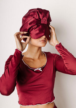 Person wearing a red satin bonnet with an eye mask attached.